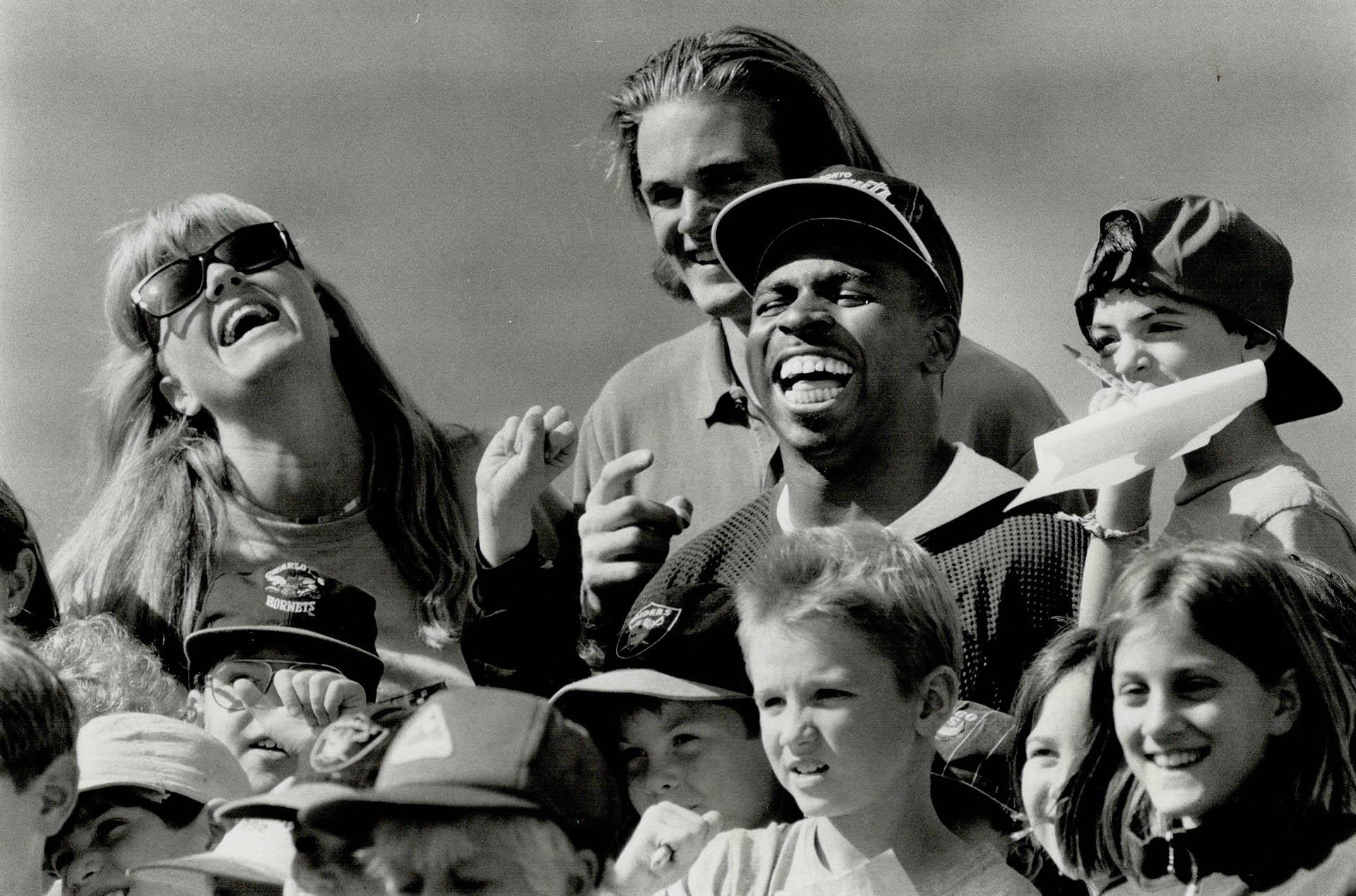 A photograph of Mike "Pinball" Clemons of the Toronto Argonauts with children and administrators from the Allenby Daycare Centre. The Toronto Star article that featured this photographed had the headline "Popular pinball: Argos standout Mike Clemons makes a bunch of the new friends from the Allenby Daycare Centre before yesterday's practice session" and was published September 4, 1992. Image by Rick Eglinton and sourced from the Toronto Public Library.