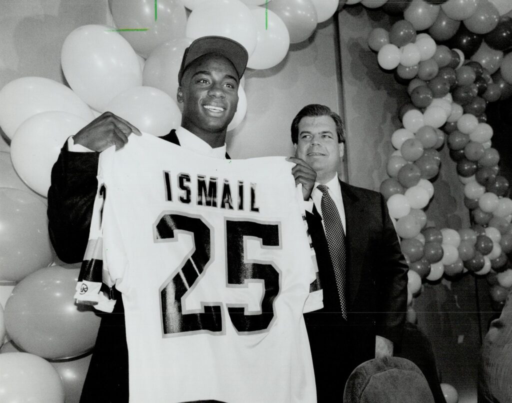 A photograph of Raghib Ismail showing off his Argonauts jersey at a celebration party shown in the Toronto Star with the headline, "Raghib Ismail: Argo receiver being treated by specialist in Los Angeles," originally published on April 23, 1991. Photographed by Rick Eglinton and sourced from the Toronto Public Library.