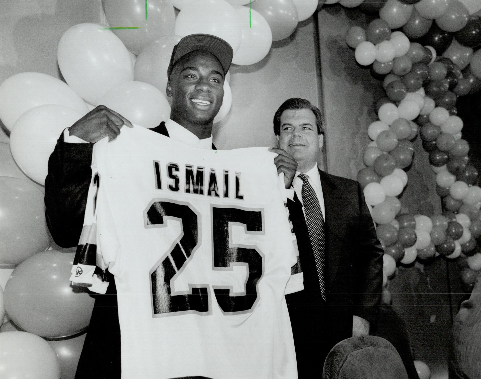 A photograph of Raghib Ismail showing off his Argonauts jersey at a celebration party shown in the Toronto Star with the headline, "Raghib Ismail: Argo receiver being treated by specialist in Los Angeles," originally published on April 23, 1991. Photographed by Rick Eglinton and sourced from the Toronto Public Library.