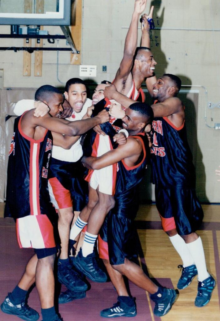A photograph of the 1995 Eastern Commerce Saints team following their championship victory over Mississauga's Westwood Wildcats in high school level basketball. Photographed by Tony Bock and sourced from the Toronto Public Library.