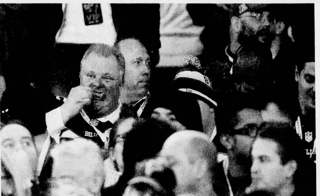 Photograph of Mayor Rob Ford eating chicken wings during one of the eight games the Buffalo Bills played at the Rogers Centre in 2013, a series of games sponsored Rogers to gauge whether there was enough of an audience in the city to justify an NFL team. Images sourced from Newspapers.com.