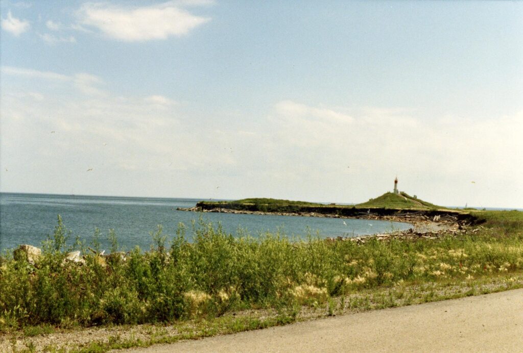 A view of the Leslie Spit looking out onto Lake Ontario. In the background, the Toronto Harbour Light, built when the Spit was first opened publicly in 1974, is visible. Sourced from Toronto Public Library.
